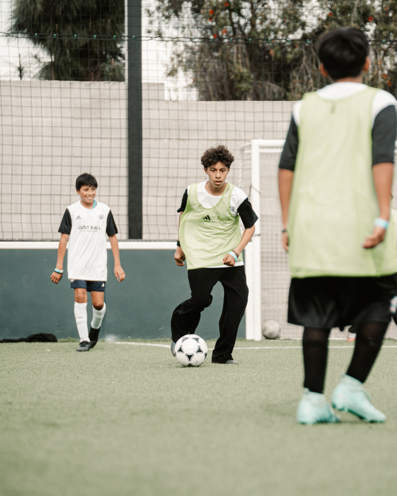 A boy dribbles a ball on a soccer field.